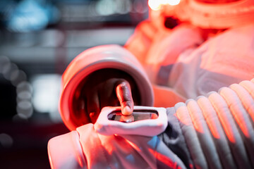 Close up of astronaut pressing wrist device under emergency red lighting to confirm alert and transmit system response. Cosmonaut activates onboard backup systems to manage critical situation © DC Studio