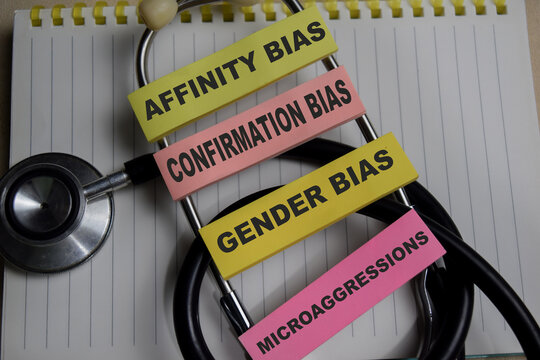Concept of 4 types of unconscious bias. Affinity, confirmation, gender, microaggressions write on sticky notes isolated on Wooden Table.
