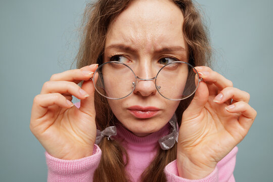 Woman adjusting round glasses closeup vision check and skeptical expression