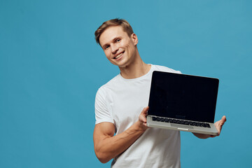 Smiling man holding laptop with black open screen, casual white t-shirt, young adult, light brown...