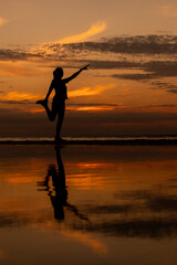 Fototapeta premium yoga and meditation. woman plays sports at sunset on the ocean. doing leg stretching, preparing for a marathon. fitness and yoga in the park, silhouette. life photo.