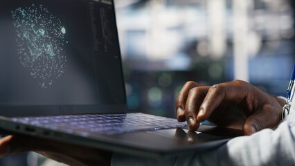 Close up of data center worker using laptop to interpret AI generated data analytics graphs. Server room technician using artificial intelligence on notebook displaying system metrics, camera B