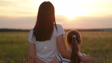 Girl child hugs mother in summer park. Mommy child embrace on sunny day. Happy daughter hugs her...
