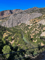 Steile Felsw&auml;nde und gr&uuml;nes Tal mit Fluss unter blauem Himmel im Gebirge Andalusiens, Naturkulisse im Sommer mit klarer Sicht und warmen Farben.