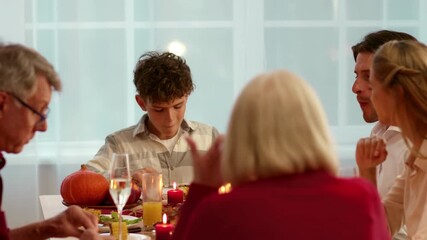 Family gathers around a table filled with Thanksgiving dishes, enjoying a festive meal. Laughter and conversation fill the air as they celebrate together in a warm, cozy atmosphere.