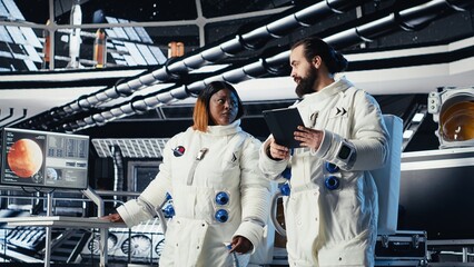 Astronaut conducting safety checks before stepping out for scheduled operations outside space station. Cosmonaut checks gear diagnostics on device, preparing to leave after landing on Mars