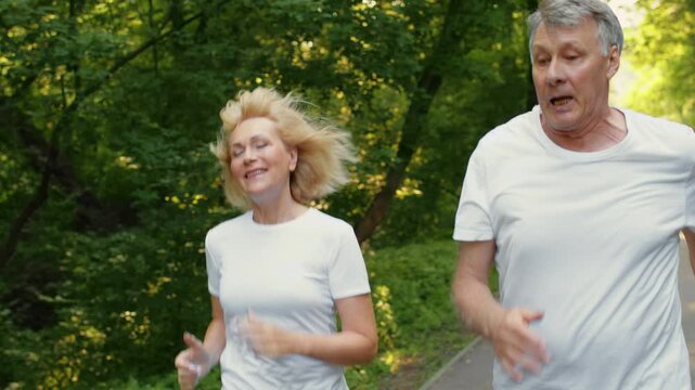 A senior couple runs happily through a lush green park, embracing an active lifestyle. Their joyful expressions reflect the benefits of staying fit at an older age.