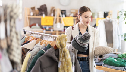 Adult woman buyer choosing warm winter hat in clothing store