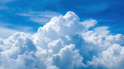 Naklejka premium Puffy white clouds float in a clear blue sky casting gentle shadows in the sunlight of midday.