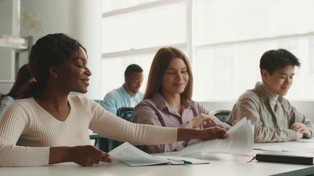 A group of diverse students collaborates on assignments in a bright study space. Each student contributes unique perspectives while discussing various topics, fostering teamwork and learning.