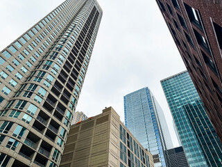 Obraz premium Low angle partial view of skyscraper building architecture in the River North neighborhood of Chicago, Illinois. Set against a soft cloudy sky.