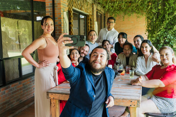 photo selfie with mobile phone of large group of friends or multi generation family eating and having a dinner in a terrace party in Mexico Latin America, portrait of hispanic people