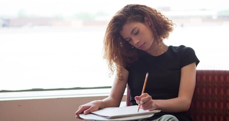 Female college student writing in notepad with pencil 4k - Powered by Adobe