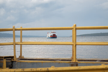 Ferry boat approaching harbor viewed through yellow railing