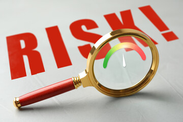 Risk. Magnifying glass with scale inside on light background
