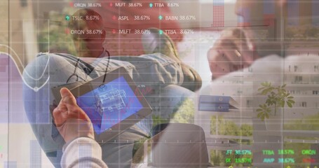 Two colleagues studying digital tablet showing blueprint in home office, with stock market overlays