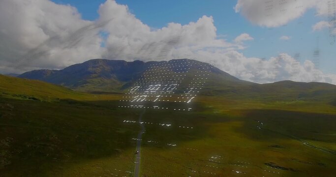 Fototapeta Displaying grassy valley and mountain ridge through window pane, with paved road and water pools