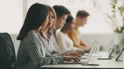 A diverse group of students is focused on their laptops while studying together in a bright, modern university setting. They are collaborating and sharing ideas for their coursework. - Powered by Adobe