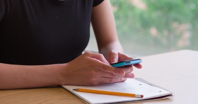 Female texting while working on homework in note pad 4k