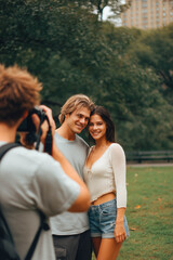 Fototapeta premium Photographer capturing a couple's portrait in a park.