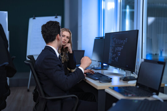 A diverse and dedicated team of professionals works diligently in a bustling, modern tech office at night, collaborating and focusing on their tasks to meet a critical project deadline.