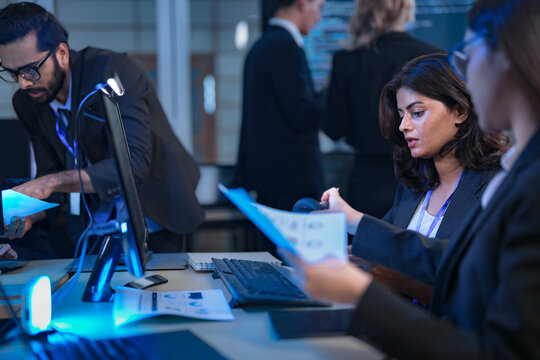A senior data scientist with glasses points out an anomaly in a machine learning model's code to two female AI engineers, as they finalize the algorithm for a new predictive analytics service.