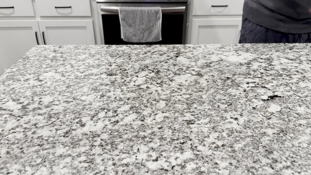 Man Wiping Down White Black Granite Countertops