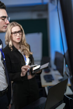 A senior software developer leads a code review session, pointing to a specific function on the screen to explain its logic and syntax to a junior engineer before a major deployment.