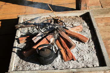 Black Rustic kettle boil water on bonfire wood burning under morning sunlight. Camping Traditional...