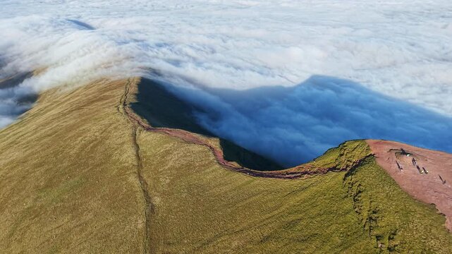 Aerial orbit of Pen-y-Fan summit in Wales with hikers above a temperature inversion