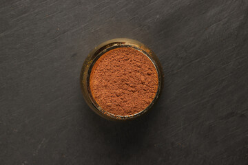 Asian spice mix powder blend in brass metal pot on a dark slate surface with a clean and neat appearance striking contrast vibrant spice top view flat lay