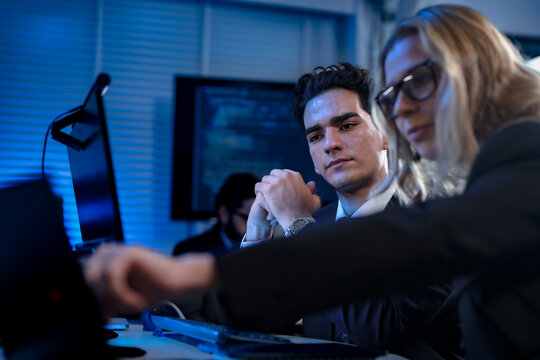 Two software developers smile with satisfaction during a pair programming session, as one points to a successfully executed block of code after solving a complex programming problem.