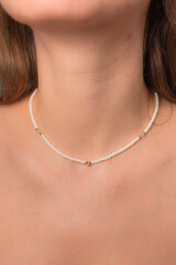 Pearl beads with metal hearts necklace on a neck of a girl