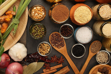 Overhead flat lay vibrant colourful spices herbs fresh produce vegetables legumes on wooden table...