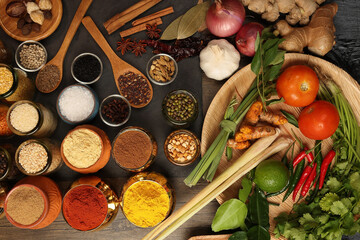 Overhead flat lay vibrant colourful spices herbs fresh produce vegetables legumes on wooden table...