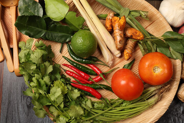 colourful fresh vegetables and herbs turmeric lemon grass lime leaf tomato red green chilli coriander on palm leaf plate wooden board for healthy cooking meals