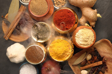 Overhead top view flat lay colourful array of spices herbs powder blue clay ceramic brass metal pot...