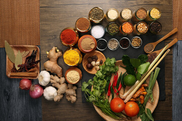 Overhead flat lay vibrant colourful spices herbs fresh produce vegetables legumes on wooden table spread splash smoking spice mix dark black slate metal clay pot palm leaf plate board copy text frame