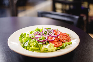 A healthy greek salad on a white plate at a restaurant