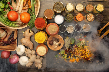 Overhead flat lay vibrant colourful spices herbs fresh produce vegetables legumes on wooden table spread splash smoking spice mix dark black slate metal clay pot palm leaf plate board copy text frame
