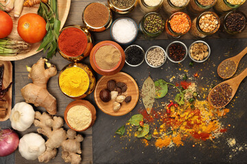 Overhead flat lay vibrant colourful spices herbs fresh produce vegetables legumes on wooden table spread splash smoking spice mix dark black slate metal clay pot palm leaf plate board copy text frame