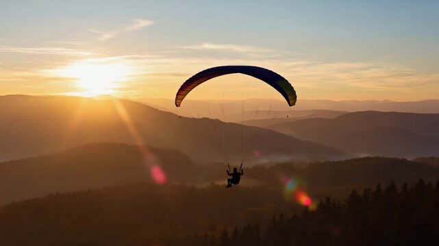 Paraglider gliding across horizon at dawn
