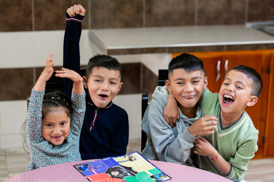 Four latin american children having fun playing board game at home