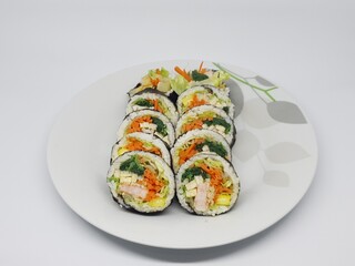 Kimbap rolls filled with vegetables and egg neatly arranged on a white plate with clean minimal background.