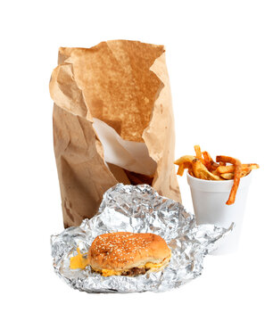 Cheeseburger, french fries in a cup, and torn paper bag on a transparent background.