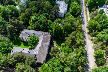 Sprawling old building with a unique roof, tucked away in vibrant green woodland. A peaceful, leafy haven from above