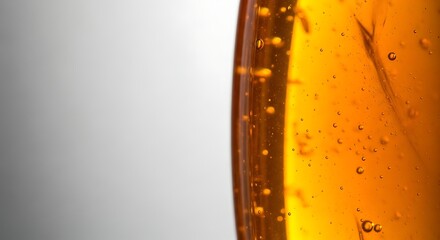 Close up of golden liquid with bubbles against a grey background creating a textured abstract image