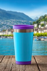 Obraz premium Colorful travel mug on wooden table overlooking scenic lake and mountain town
