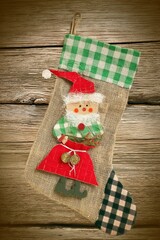 Christmas Stocking with Santa Ornament on Wood Background.