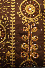 Obraz premium Overhead view of brown and gold beaded lace fabric, top view of nigerian george fabric for making traditional wedding attire